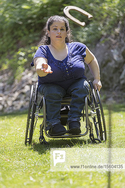 Frau mit Spina Bifida im Rollstuhl spielt Hufeisen