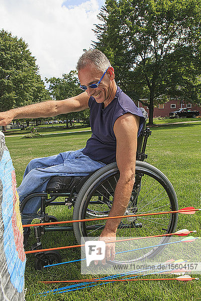 Mann mit Rückenmarksverletzung im Rollstuhl entfernt Pfeile von der Zielscheibe nach einem Bogenschießtraining