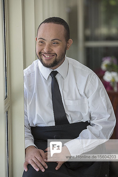 Glücklicher afroamerikanischer Mann mit Down-Syndrom als Kellner in einem Restaurant