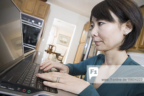 Side profile of a mid adult woman using a laptop