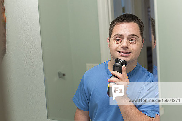Mann mit Down-Syndrom rasiert sich im Badezimmer