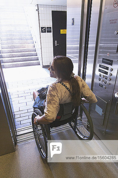 Woman with spinal cord injury in a wheelchair using elevator to train access
