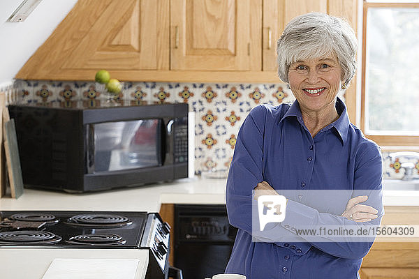Porträt einer fröhlichen Frau  die in einer Küche steht.