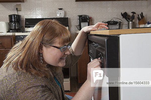 Eine blinde Frau startet den Geschirrspüler in ihrer Küche