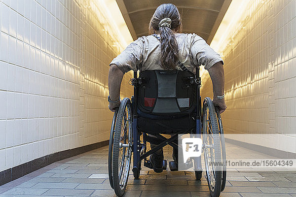 Frau mit Querschnittslähmung im Rollstuhl beim Betreten einer U-Bahn-Station