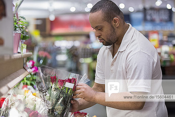 Mann mit Down-Syndrom pflückt Blumen in einem Geschäft