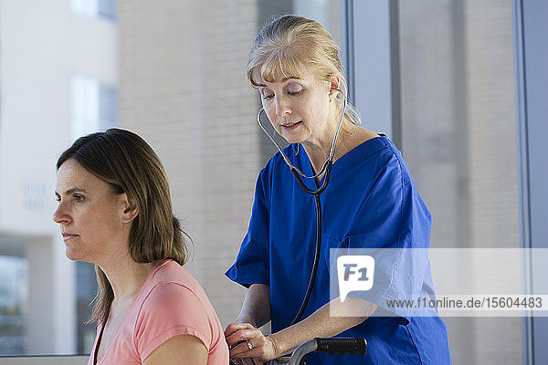 Krankenschwester überprüft einen Patienten mit einem Stethoskop