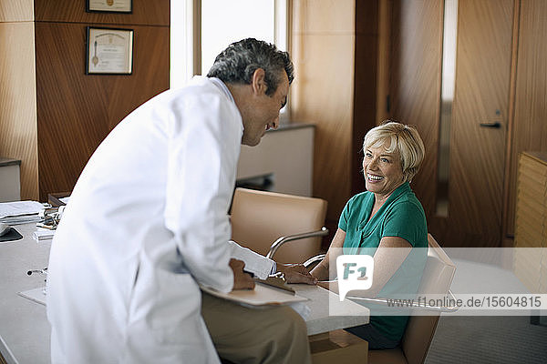 Älterer Arzt berät einen Patienten in seiner Praxis