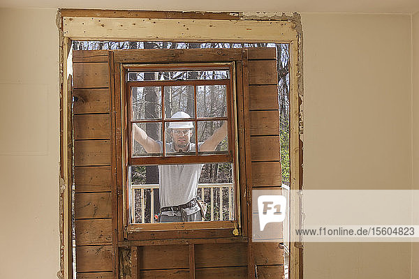 Hispanischer Schreiner beim Entfernen der neu geschnittenen Tür zum Deck eines Hauses