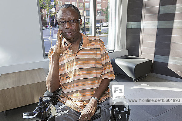 Man with Guillain-Barre Syndrome on wheelchair in front of the apartment window
