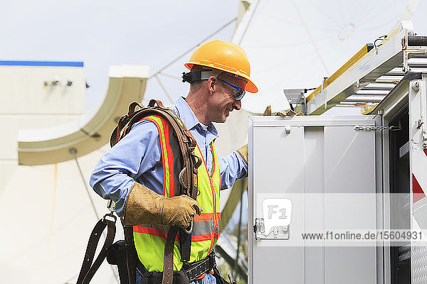 Communications engineer getting equipment from truck with satellite antenna in background