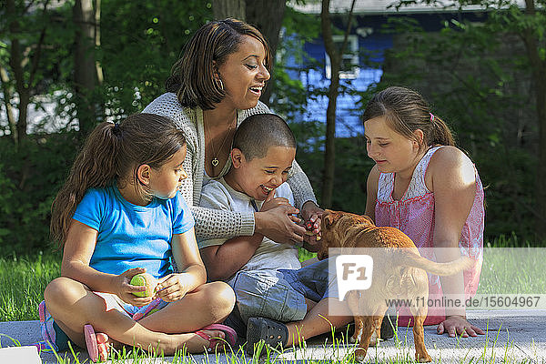 Hispanic family with Autistic boy playing with a dog in park