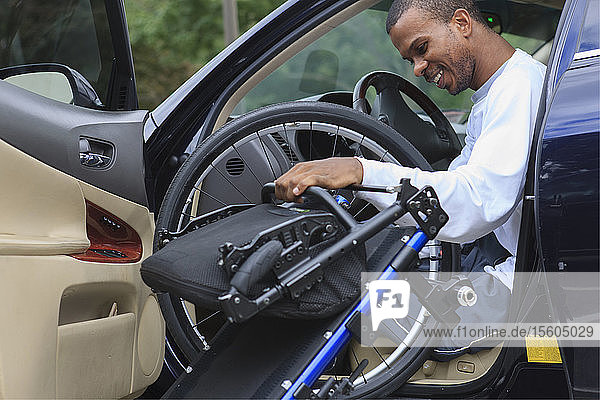 Man who had Spinal Meningitis entering his car with his wheelchair
