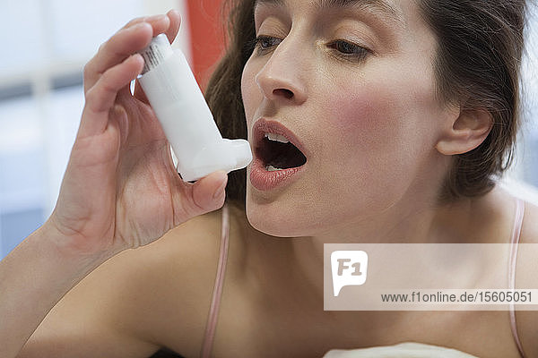 Nahaufnahme einer mittelgroßen erwachsenen Frau  die einen Asthma-Inhalator benutzt