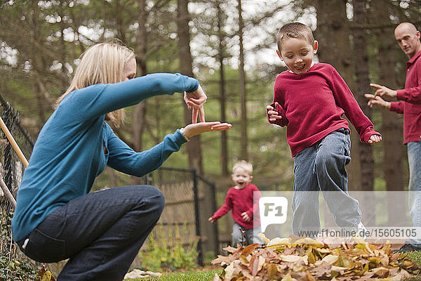 Frau  die das Wort Jump in amerikanischer Gebärdensprache gebärdet  während sie mit ihrem Sohn in einem Park kommuniziert