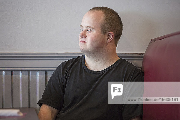 Waiter with Down Syndrome sitting on chair in a restaurant