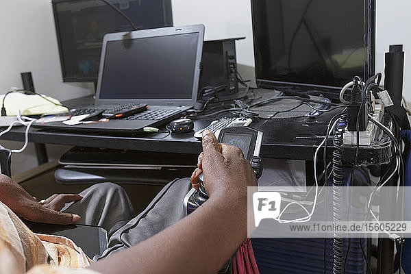 Mann mit Guillain-Barre-Syndrom bei der Nutzung seiner technischen Geräte im Heimbüro