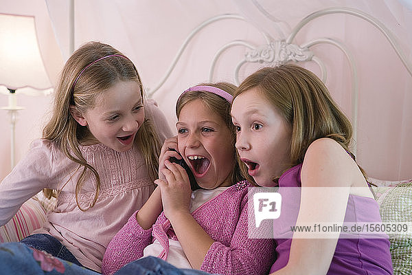 Three young girls listening on a phone