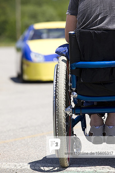 Person im Rollstuhl mit Blick auf den Rennwagen  Rückansicht