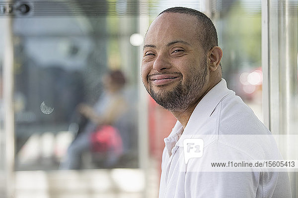 Man with Down Syndrome sitting at a bus stop
