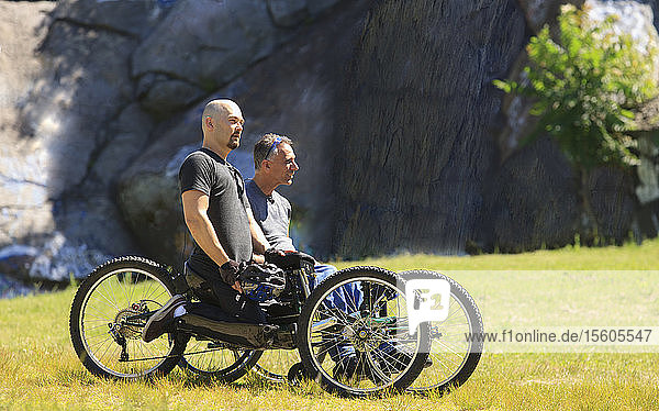 Zwei Männer mit Rückenmarksverletzungen fahren auf geländegängigen Handbikes