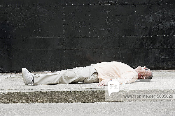 Ein älterer Mann liegt auf einer Straße.
