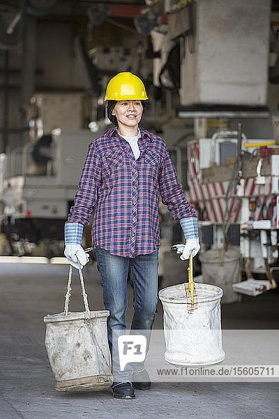 Eine Ingenieurin bereitet in einer Werkstatt in der Nähe eines Lastwagens einen Eimer aus Segeltuch vor.