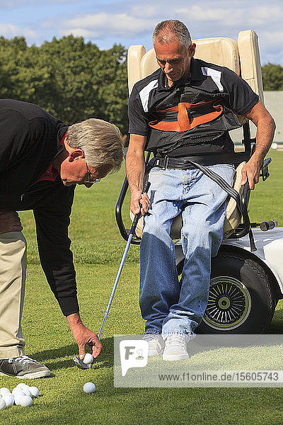 Golflehrer platziert Golfball für Mann mit Rückenmarksverletzung