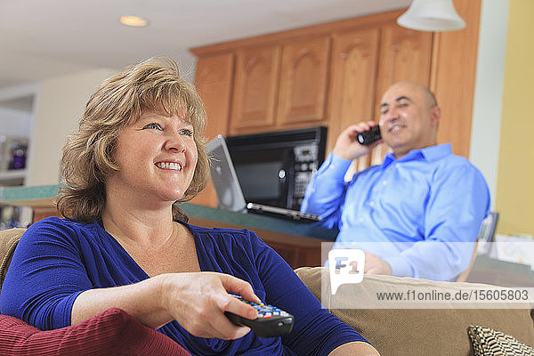 Ehefrau benutzt TV-Fernbedienung und Ehemann benutzt Telefon