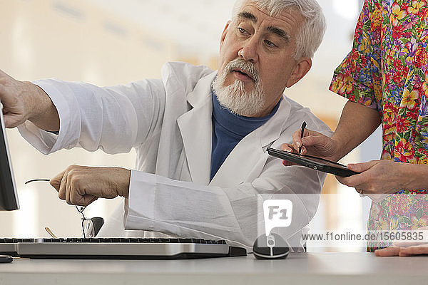 Arzt und Krankenschwester in einer Konferenz mit Computer und Tablet. Arzt hat Muskeldystrophie