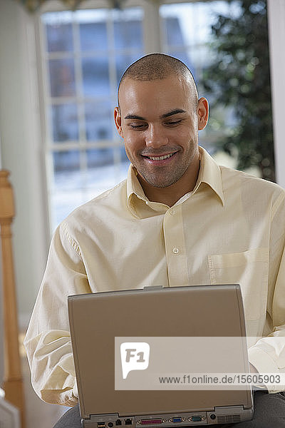 Hispanic man working on a laptop and smiling