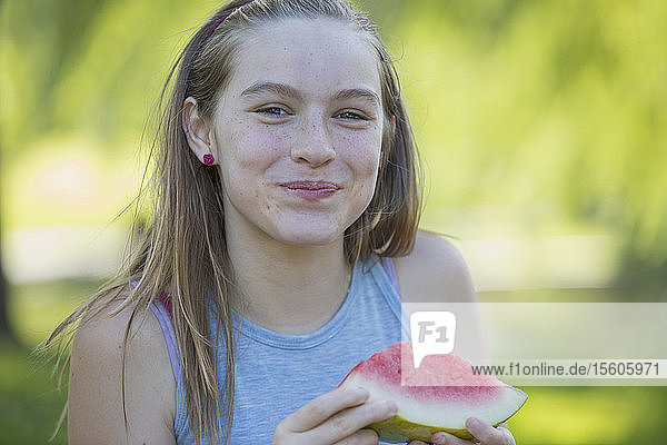Porträt eines glücklichen hispanischen Teenagers  der eine Wassermelone isst