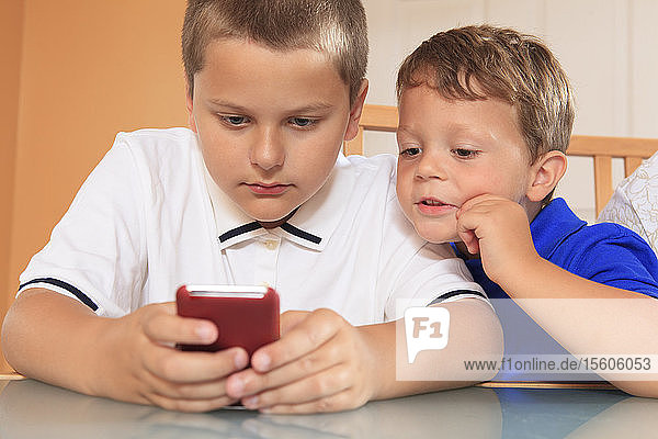 Junge Jungen spielen mit ihrem Mobiltelefon