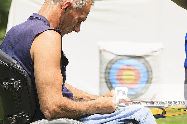 Mann mit Rückenmarksverletzung bereitet Pfeil und Bogen für Zielübungen vor