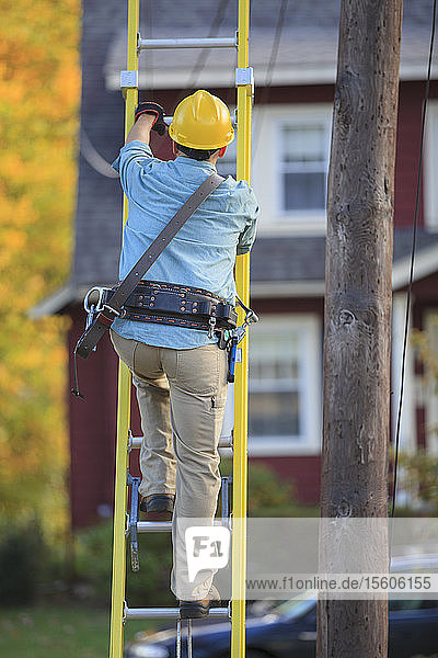 Elektriker klettert auf Leiter an Strommast