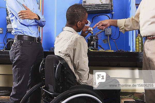 Instructor discussing condenser coil on refrigeration unit with student in wheelchair