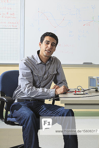 Engineering student sitting in classroom with oscilloscope and electronic prototyping breadboard