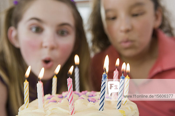 Zwei Mädchen blasen die Kerzen auf einer Geburtstagstorte aus