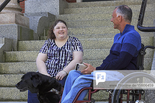 Mann mit Rückenmarksverletzung sitzt neben seiner blinden Tochter
