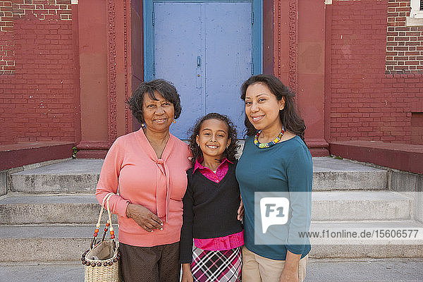 Hispanische Mutter und Großmutter verabschieden ihre Tochter in die Grundschule