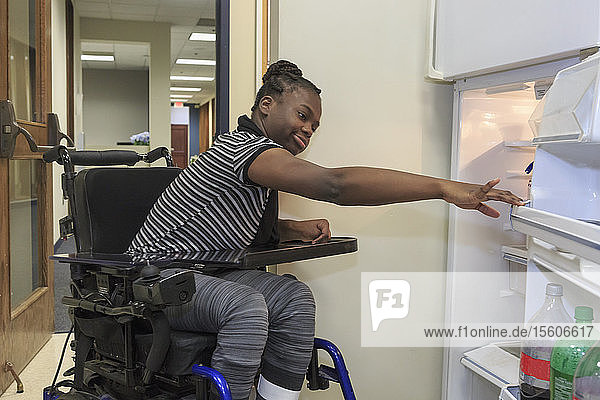 Teen with Cerebral Palsy opening refrigerator in the kitchen