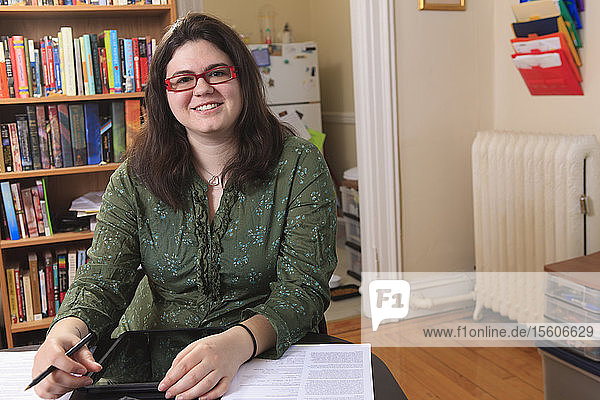 Frau mit Asperger-Syndrom arbeitet in ihrem Heimbüro mit ihrem Tablet