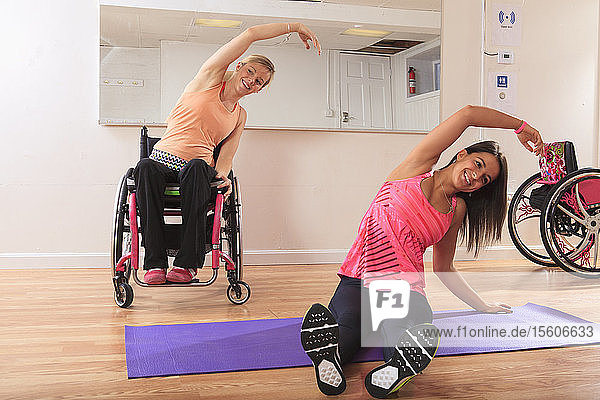 Junge Frauen mit Rückenmarksverletzungen bei Übungen in einem Yogastudio