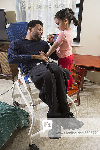 Afroamerikanischer Mann mit zerebraler Lähmung mit seiner Tochter zu Hause