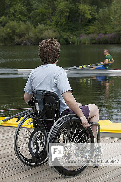 Frau mit Querschnittslähmung sitzt im Rollstuhl auf dem Steg