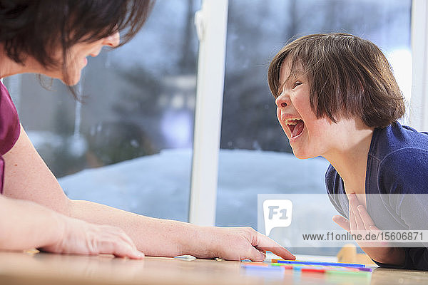 Kleines Mädchen mit Down-Syndrom spielt ein Lernspiel mit ihrer Mutter