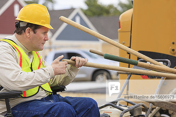 Construction supervisor with Spinal Cord Injury counting work tools on construction site