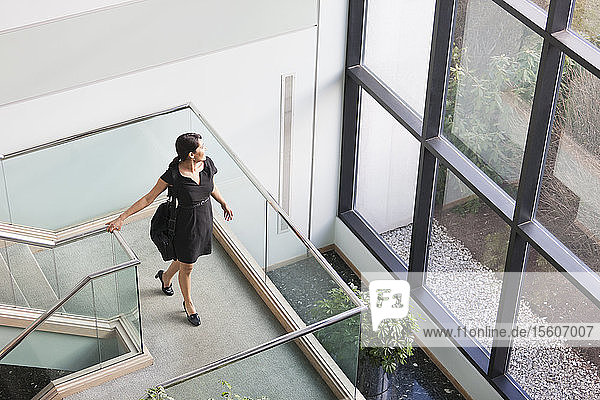 Hispanische Geschäftsfrau mit Aktentasche auf der Treppe eines Bürogebäudes