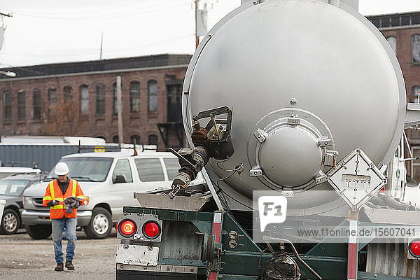 Umwelttechniker telefoniert mit Tankwagen bei der Beseitigung von Sondermüll