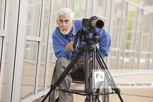 Videographer with muscular dystrophy and diabetes in his wheelchair using video camera